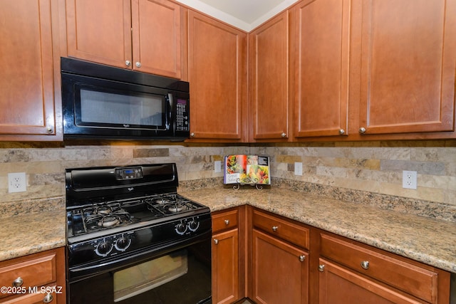 kitchen with black appliances, tasteful backsplash, and light stone countertops