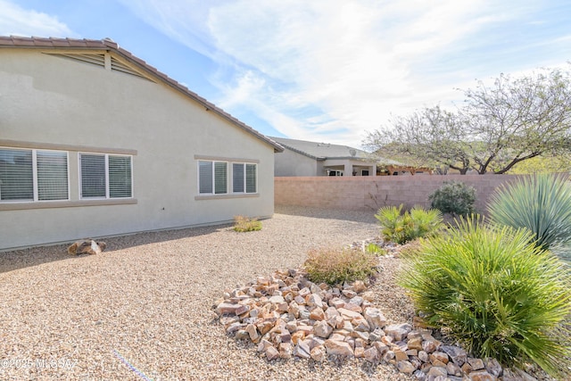 rear view of house with a tile roof, a fenced backyard, and stucco siding