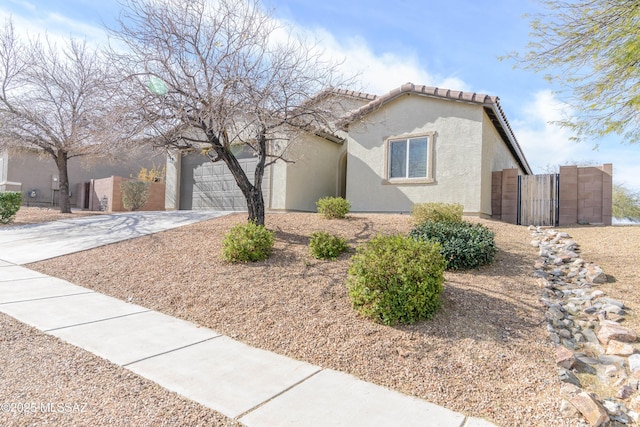 view of front of house featuring a garage, a tile roof, concrete driveway, a gate, and stucco siding