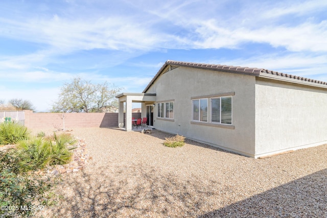 rear view of house featuring a tile roof, a patio area, a fenced backyard, and stucco siding