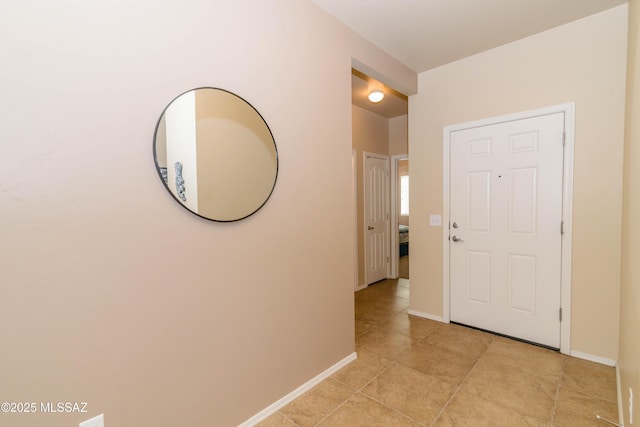 hallway featuring baseboards and light tile patterned floors