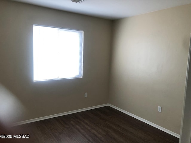 unfurnished room with dark wood-style floors, plenty of natural light, and baseboards