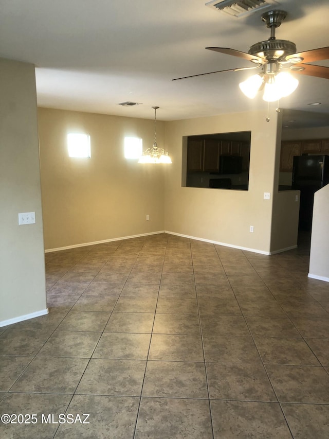 unfurnished room featuring visible vents, dark tile patterned floors, baseboards, and ceiling fan with notable chandelier