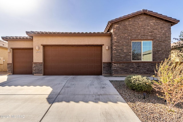 view of front of property featuring driveway, stone siding, an attached garage, and stucco siding