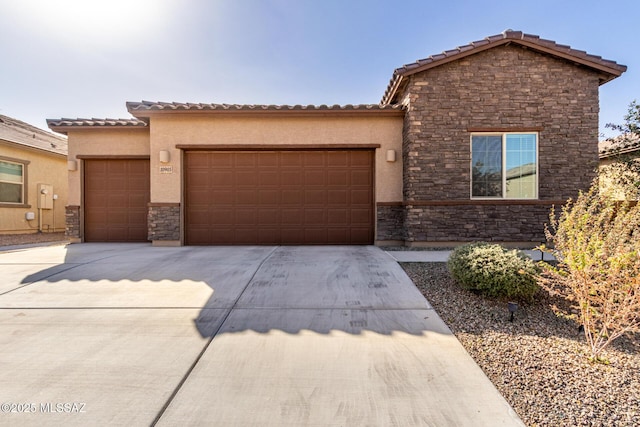 view of front of house featuring a garage, driveway, stone siding, and stucco siding