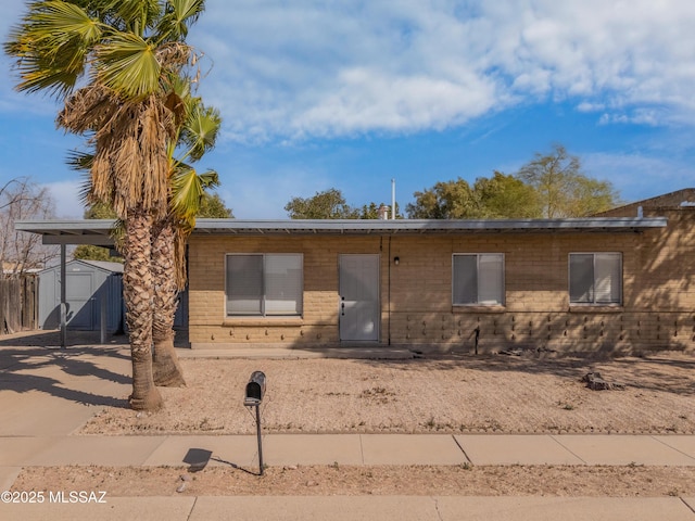 view of front of property featuring a carport, an outdoor structure, driveway, and a storage unit