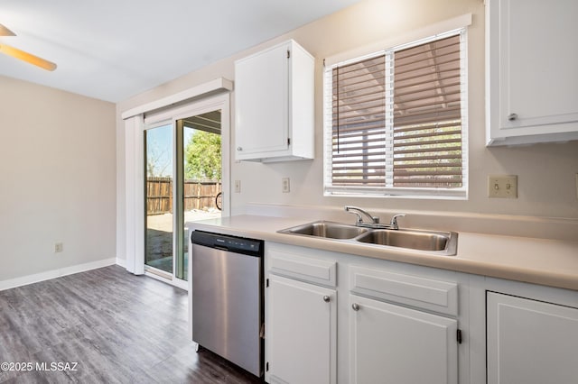 kitchen with dark wood-type flooring, light countertops, stainless steel dishwasher, white cabinetry, and a sink