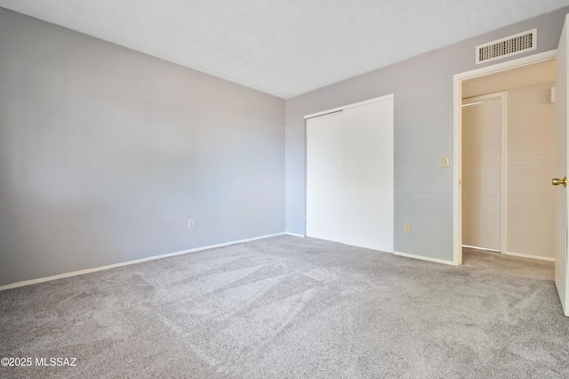 unfurnished bedroom with carpet, a closet, visible vents, and a textured ceiling