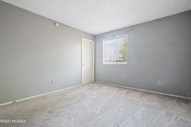 spare room featuring carpet floors, a textured ceiling, and baseboards