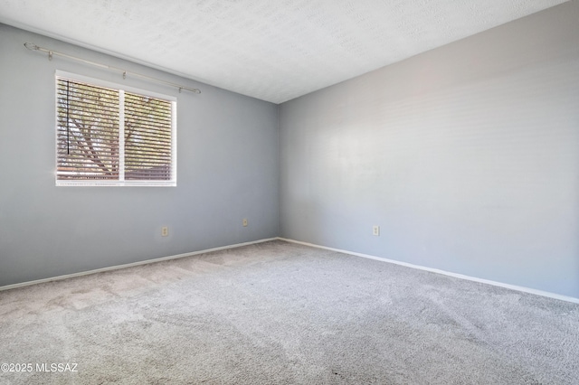 carpeted spare room featuring a textured ceiling and baseboards