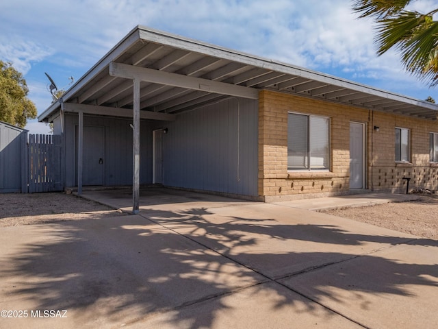 exterior space featuring a carport, fence, and concrete driveway