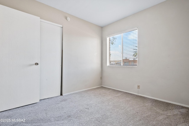 unfurnished bedroom with a closet, carpet flooring, and baseboards