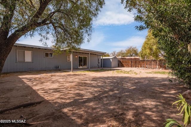 rear view of property featuring a shed, fence, and an outdoor structure