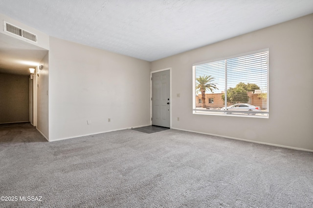 carpeted spare room featuring a textured ceiling, visible vents, and baseboards