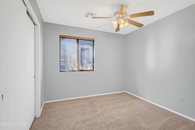 carpeted empty room featuring baseboards, visible vents, and a ceiling fan