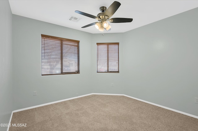 carpeted empty room with a ceiling fan, visible vents, and baseboards