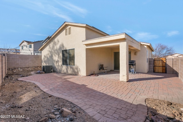 rear view of house with a gate, a fenced backyard, a patio, and stucco siding