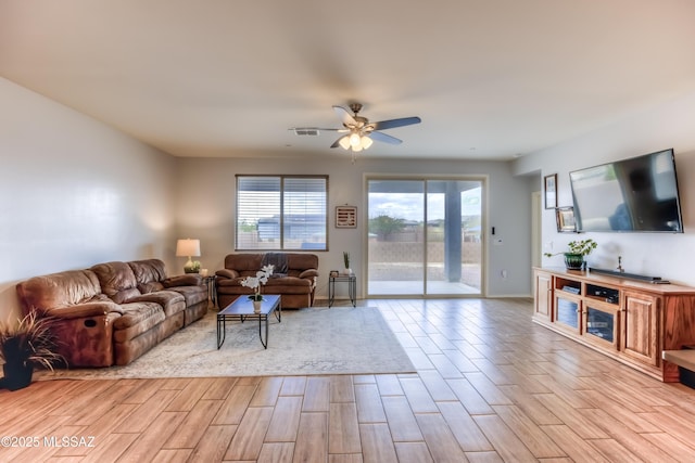 living area featuring ceiling fan, light wood finished floors, visible vents, and baseboards