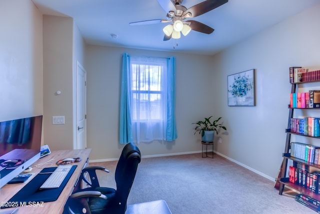 carpeted office space with a ceiling fan and baseboards