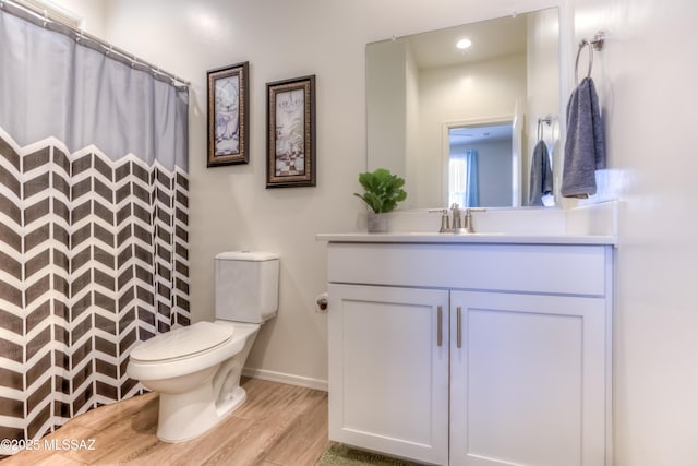 bathroom featuring curtained shower, toilet, wood finished floors, vanity, and baseboards