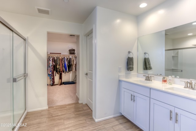 bathroom featuring a stall shower, a walk in closet, visible vents, and a sink