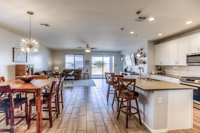 kitchen featuring open floor plan, appliances with stainless steel finishes, a sink, and visible vents