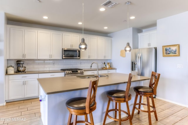 kitchen featuring tasteful backsplash, visible vents, stainless steel appliances, and a sink