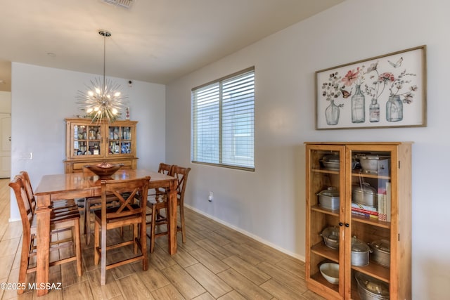 dining area with an inviting chandelier, wood tiled floor, visible vents, and baseboards