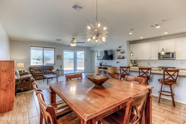 dining room with ceiling fan with notable chandelier, light wood-style flooring, visible vents, and recessed lighting