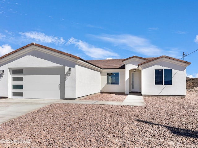 mediterranean / spanish-style home with a garage, concrete driveway, a tile roof, and stucco siding