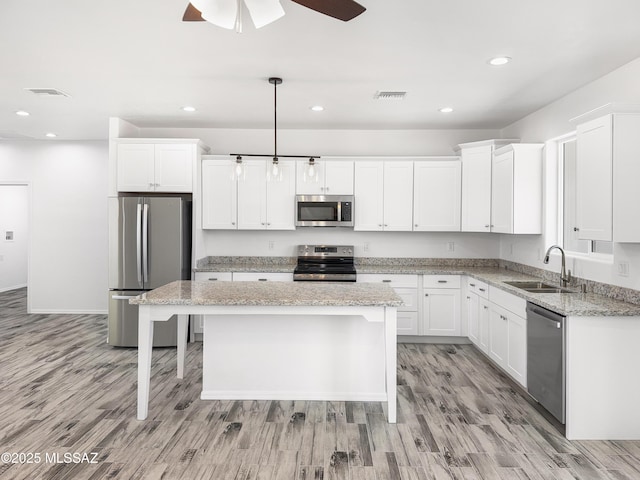 kitchen with appliances with stainless steel finishes, a sink, visible vents, and white cabinetry