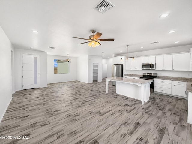 kitchen featuring a center island, visible vents, appliances with stainless steel finishes, open floor plan, and a kitchen bar