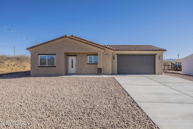 single story home with a garage, driveway, a tiled roof, and stucco siding