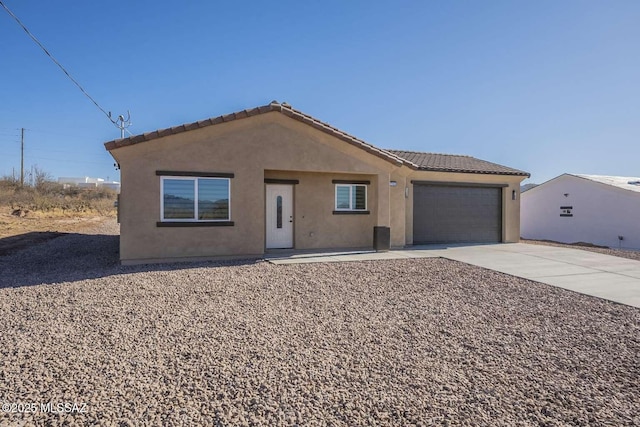 view of front of home featuring a garage, concrete driveway, a tiled roof, and stucco siding