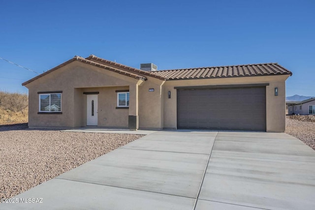 view of front of home with a garage, driveway, a tile roof, and stucco siding