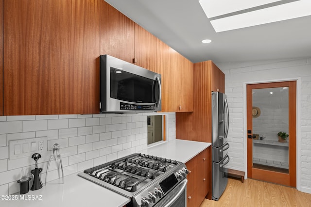 6530 N Camino De La Karina, Tucson, AZ 85718 - kitchen with stainless steel appliances, a skylight, light wood-style floors, backsplash, and brown cabinets