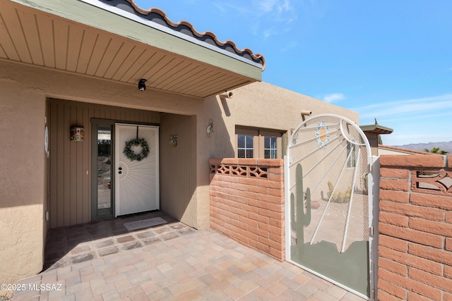 entrance to property featuring a tiled roof and stucco siding