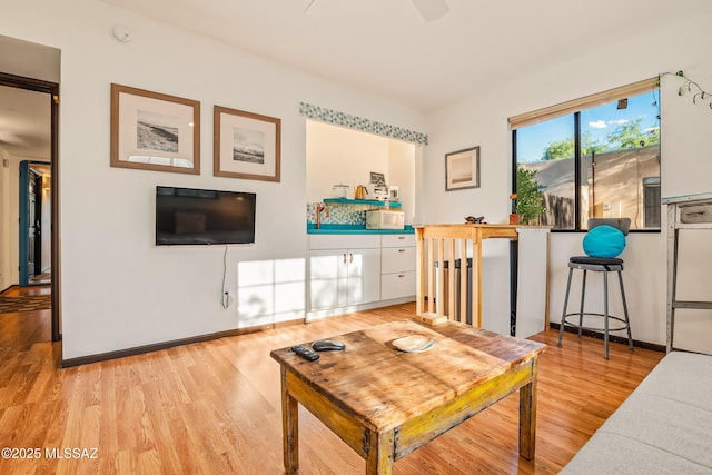 living area featuring baseboards and light wood finished floors