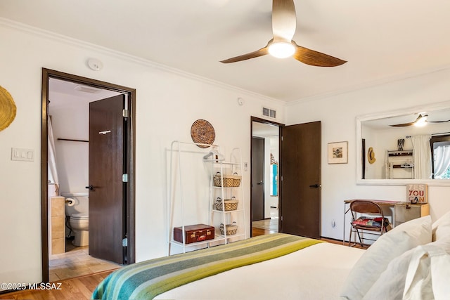 bedroom featuring visible vents, a ceiling fan, wood finished floors, ensuite bathroom, and crown molding