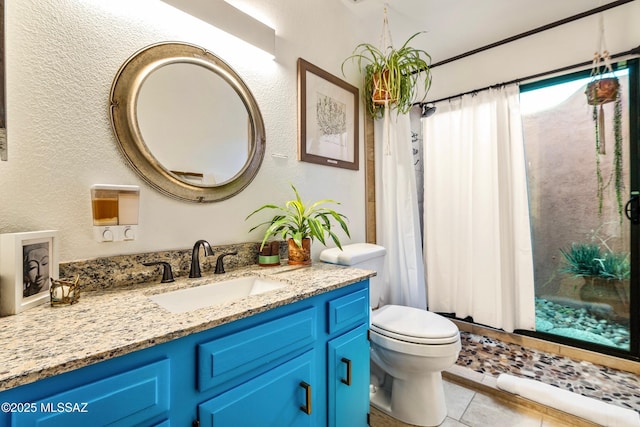 full bath with curtained shower, a textured wall, toilet, vanity, and tile patterned floors