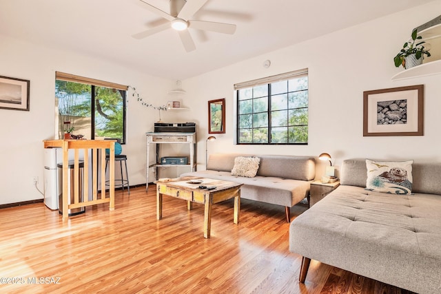 living area featuring light wood-style floors, baseboards, and a ceiling fan