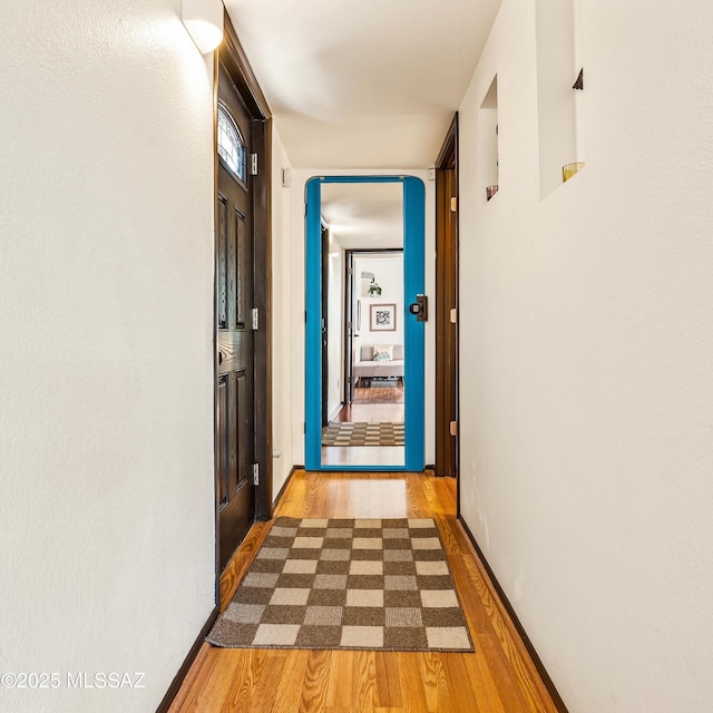 corridor featuring baseboards and wood finished floors