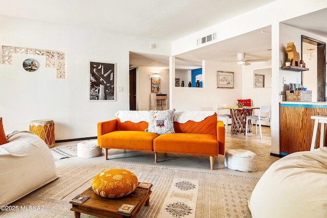 living area with visible vents, ceiling fan, and baseboards