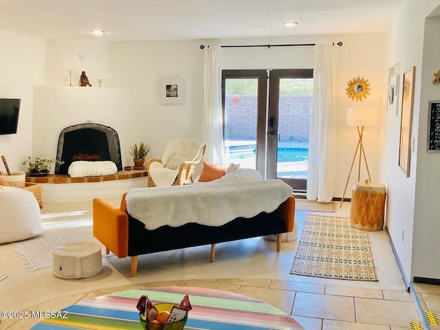 bedroom featuring baseboards, a fireplace with raised hearth, tile patterned floors, access to outside, and french doors