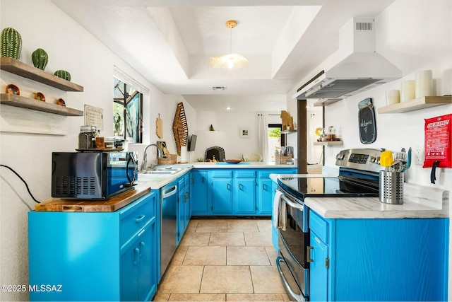 kitchen featuring stainless steel appliances, blue cabinetry, range hood, open shelves, and a tray ceiling