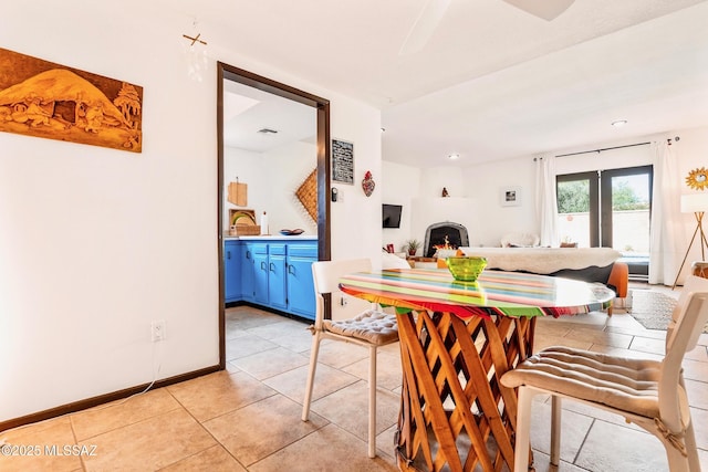 dining area with light tile patterned floors, a lit fireplace, visible vents, and baseboards