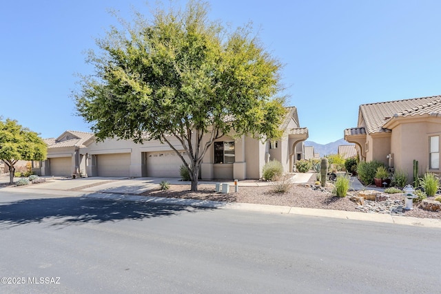 view of front facade with a tile roof, stucco siding, concrete driveway, and a garage