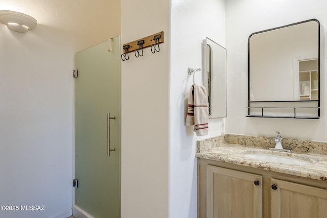 bathroom featuring a shower with shower door and vanity