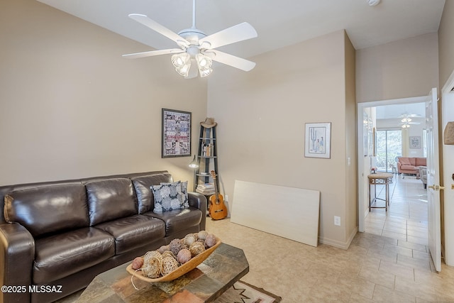 living area with baseboards, ceiling fan, and a towering ceiling