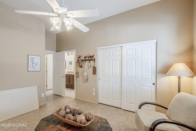 living area with light tile patterned floors, baseboards, and ceiling fan